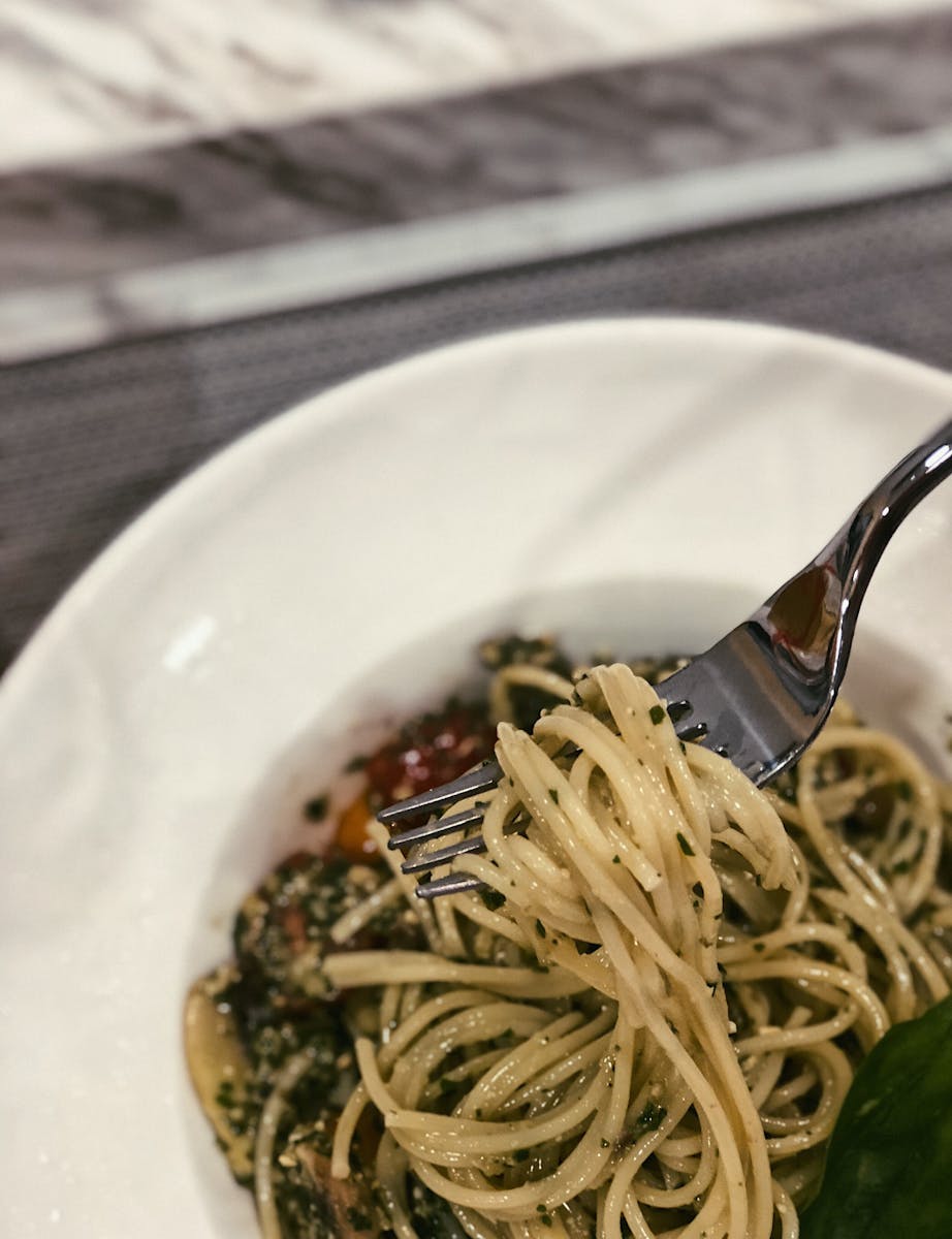 Savor a forkful of flavorful spaghetti with herbs, captured in a mouthwatering close-up.