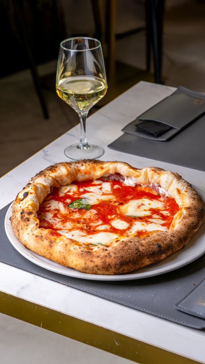 Tasty Margherita pizza paired with white wine, classic Italian dining setup.