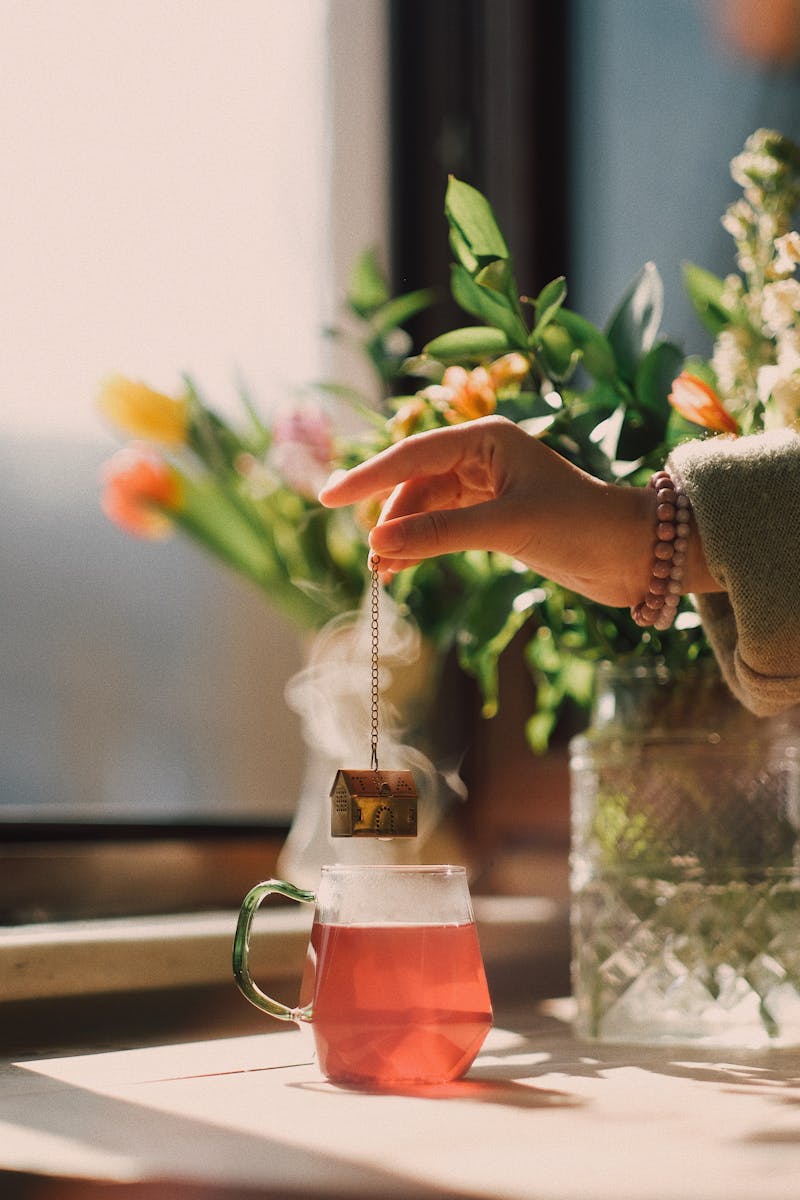 A peaceful scene of tea brewing near a window with flowers in soft sunlight.